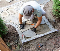 An image of a
          landscaper laying down some outdoor stonework