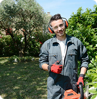 An image of an employee, smiling and holding a weed whacker