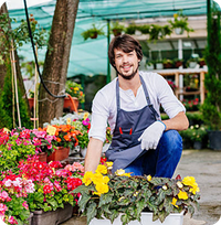 An image of an employee, smiling, kneeling by a bed of flowers